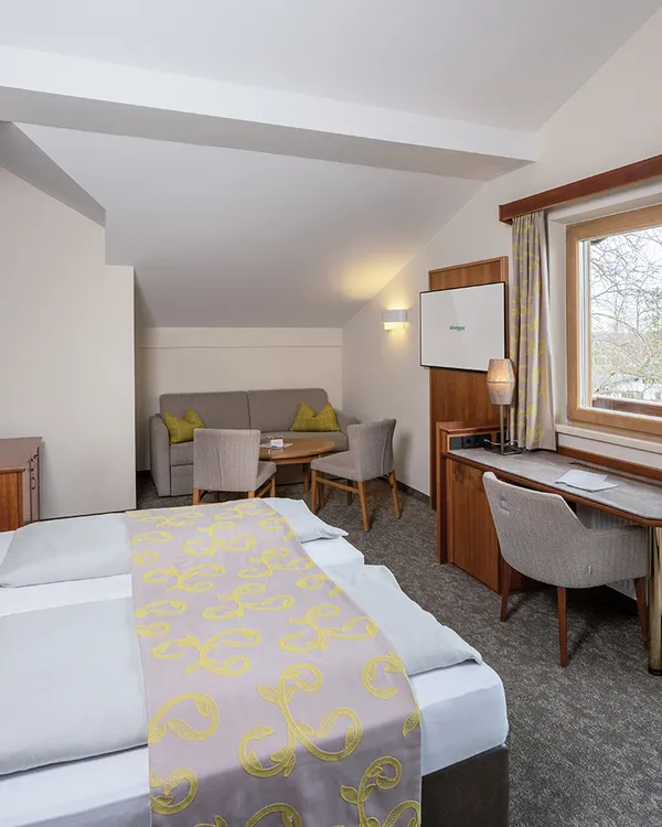 Gemütliches Hotelzimmer mit Doppelbett, Sitzecke, Schreibtisch und Balkonblick